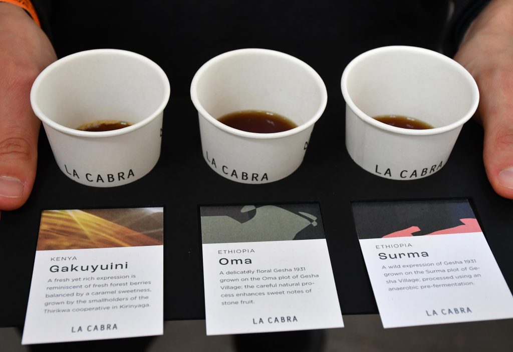 3 kelímky se vzorky kávy od pražírny La Cabra s informačními kartami z Prague Coffee Festivalu.